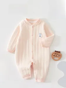 Detail of pink long sleeve baby romper with ribbed texture and smiley face patch