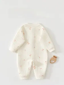 Detail of baby romper featuring beige ribbed cotton fabric with red cherry and bow print