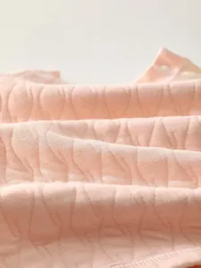 Détail du tissu matelassé rose pour bébé avec motif en losanges respirant