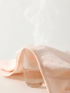 Pink newborn cotton romper showing high breathability with steam passing through the fabric
