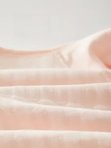 Close-up of soft pink knitted cotton fabric showing breathable texture for baby clothing