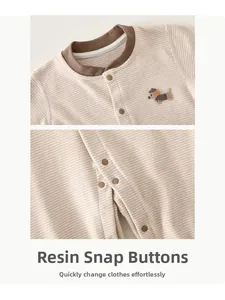 Detail view of resin press studs and striped cashmere-silk fabric on baby jumpsuit