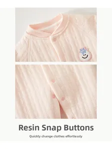 Detail of pink cotton baby romper with resin snap buttons and soft geometric texture