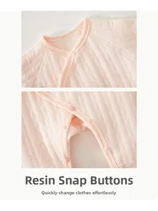 Detail of pink padded baby bodysuit showing resin snap buttons and quilted honeycomb texture