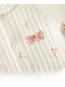 Close-up of baby romper featuring cherry prints and a pink knitted 3D bow detail