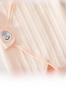 Detail of pink quilted infant romper with jacquard texture and star smiley face patch
