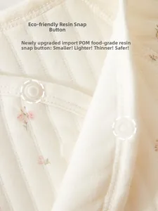 Detail eines Baby-Einteilers mit rosa Blumenmuster und Druckknöpfen aus lebensmittelechtem Harz