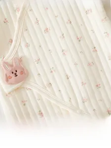 Detail von gestepptem Baby-Strampler aus Baumwolle mit Blumenmuster und Hasen-Aufnäher