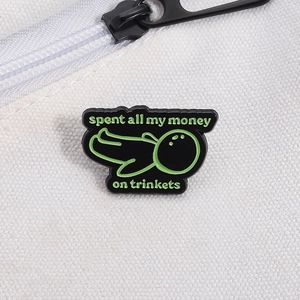 Detailed macro shot of an enamel brooch with green Spent All My Money On Trinkets text