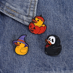 Detail of Halloween enamel pins with rubber duck pumpkin and witch designs on denim
