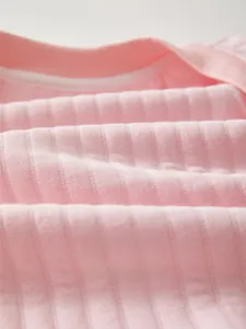 Close-up of soft pink ribbed cotton fabric detail showing breathable mesh texture