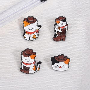 Detailansicht von vier Cowboy-Katzen-Emaille-Pins an weißem Canvas-Stoff befestigt