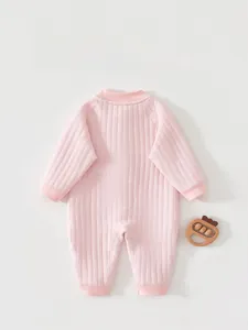 Macro detail of pink quilted baby romper with ribbed cuffs and textured knit fabric