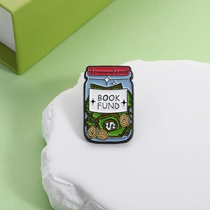 Detail shot of a creative money jar enamel pin featuring Book Fund text and coin icons