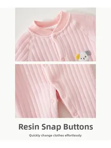 Detailed view of resin snap fasteners and puppy embroidery on quilted baby romper