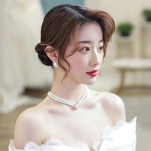 Gros plan sur le collier de perles double couche et les boucles d'oreilles sur modèle