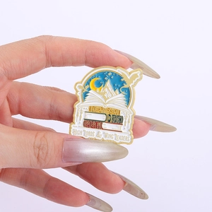 Detailed macro shot of a fantasy dragon and book enamel pin with gold plating finish