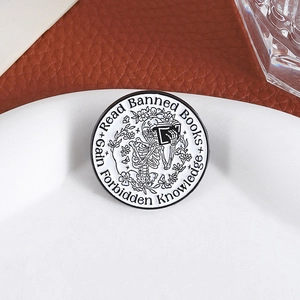 Gothic skull reading books enamel pin with 'Read Banned Books' text on white tray