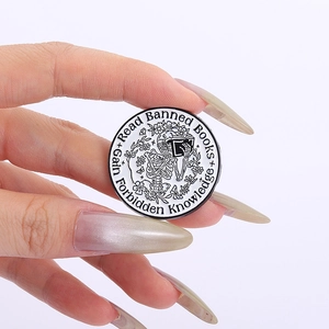 Detail of round skull brooch reading a book with Read Banned Books text and floral trim