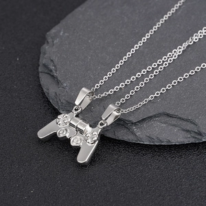Close-up of magnetic game controller pendant necklaces for couples on a dark stone surface