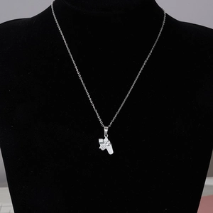 Detailed macro view of a silver gaming controller pendant on a black jewelry stand