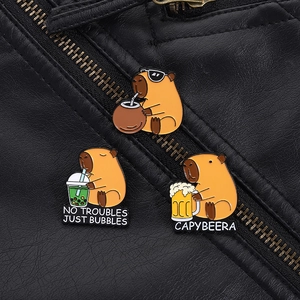 Three enamel capybara pins styled on a black leather jacket featuring beer and boba motifs
