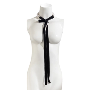 Detail van fluwelen choker ketting met strik en parels op een display mannequin pop