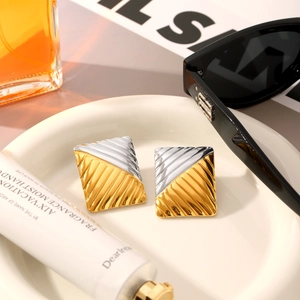 Macro view of two-tone geometric earrings with textured surface on a ceramic plate