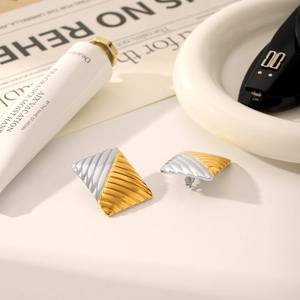 Close-up of square gold and silver two-tone earrings with elegant pleated metal texture