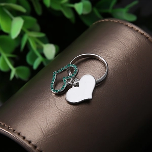Bague cœur argentée avec pavé de pierres vertes et breloque polie sur support