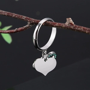 Bague cœur infini en argent avec cristaux verts sur fond de branche rustique