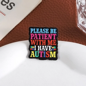 Enamel autism awareness pin badge featuring puzzle pieces on white ceramic plate