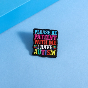 Détail macro du badge en émail pour l'autisme avec texte multicolore et symboles de puzzle