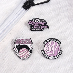 Trois pin's émaillés avec chat noir et planètes sur un sac en toile blanche