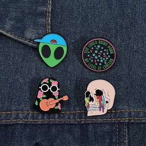 Detailed close-up of colorful enamel pins featuring alien and skull designs on denim jacket