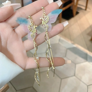Elegant gold butterfly wing earrings with long tassels and crystal stones in hand