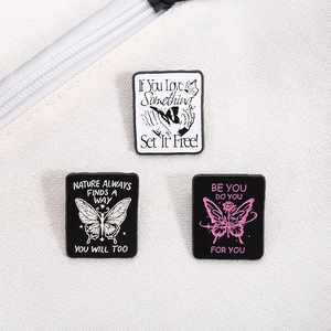 Three enamel butterfly pins attached to a white canvas bag with motivational quotes