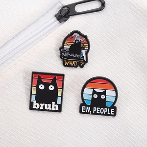 Detailed view of three cartoon black cat enamel pins pinned on a white canvas backpack