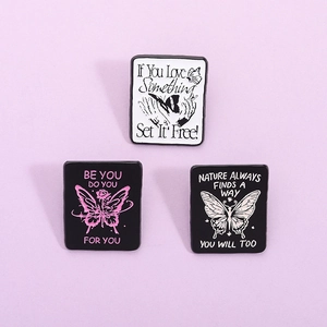 Three enamel butterfly brooches with inspirational quotes on pink and purple background