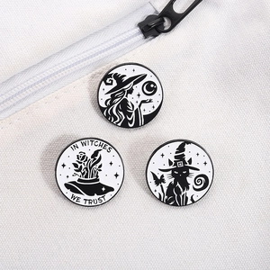 Detailed macro of black and white enamel pins with magic cat and witch motifs