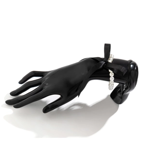 Detailopname van parelarmband met zwarte satijnen strik op een elegant model