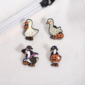 Close-up of four Halloween enamel pins featuring cute ghost, mummy, and pumpkin ducks