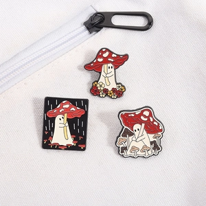Detailed view of three cartoon ghost and mushroom enamel pins on white canvas fabric