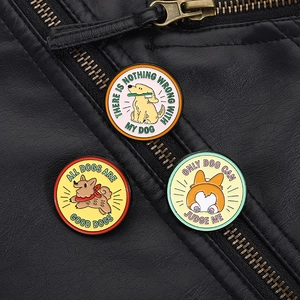 Detail von süßen Hunde-Emaille-Pins mit lustigen Sprüchen auf einer Lederjacke