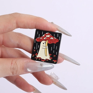 Macro shot of an enamel ghost pin with a mushroom umbrella held by a hand