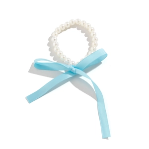 Detail van parelketting met een lichtblauwe satijnen strik en lange hangende linten