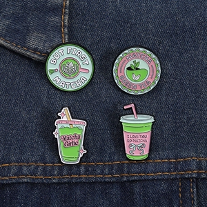 Detail of four creative matcha-themed enamel pins displayed on a blue denim jacket