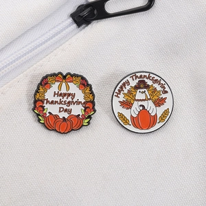 Detail of enamel pins featuring a turkey and pumpkin with Happy Thanksgiving Day text