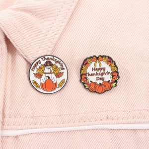 Detailed close-up of Thanksgiving enamel pins with turkey and pumpkin on denim jacket