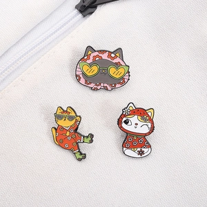 Detailed view of three cartoon cat enamel pins on white canvas bag with vibrant colors